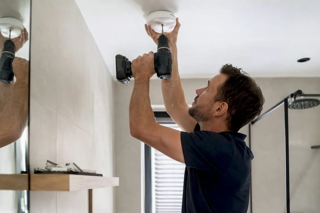 Het plafond boren om de bevestigingsplaat van de rookmelder te installeren